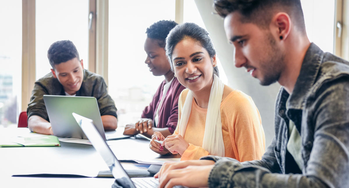 Image of young adults at computers working together