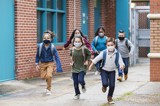 图像在室外跑步上学的孩子,戴着面具