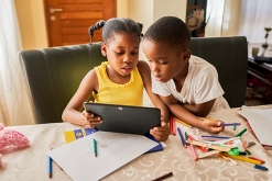 图像的年轻男孩和女孩一起看平板电脑