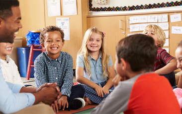 老师坐在教室地板上的孩子微笑