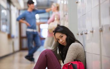 年轻女子坐在学校走廊的洛克的地板上