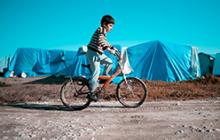 叙利亚男孩在难民营中骑自行车的图像