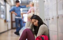 年轻女子坐在地板上在学校走廊里储物柜