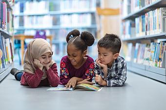 三个年幼的孩子一起在图书馆里读书